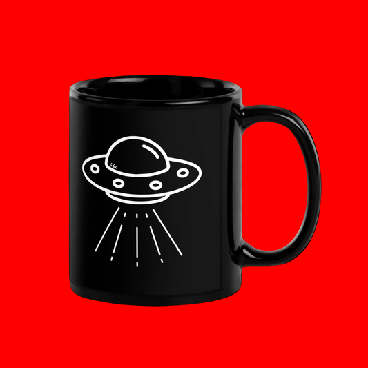 A glossy black ceramic mug featuring a white line-art graphic of a flying saucer UFO, set against a solid bright red background.